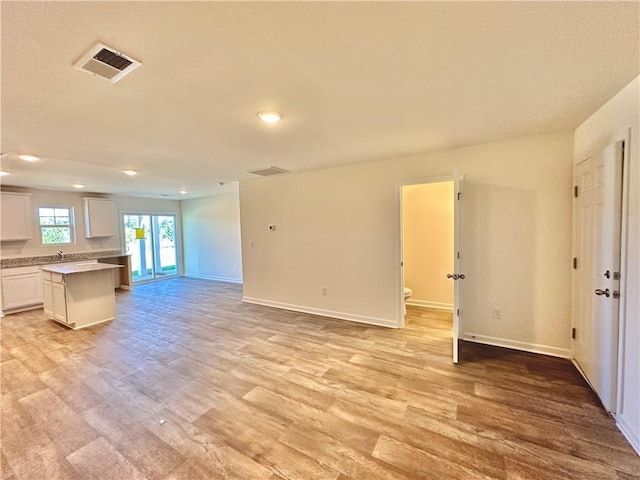 unfurnished living room featuring sink and light hardwood / wood-style flooring