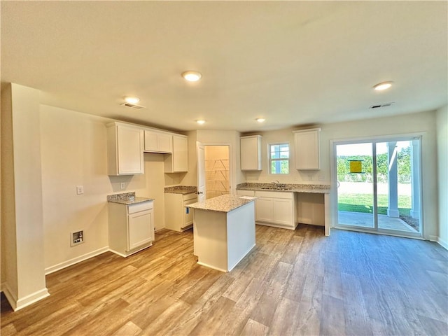 kitchen with a center island, light hardwood / wood-style flooring, and white cabinets