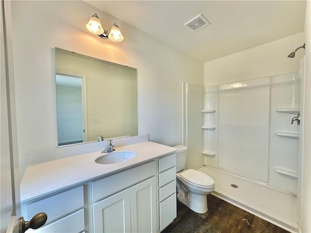 bathroom featuring a shower, hardwood / wood-style floors, vanity, and toilet