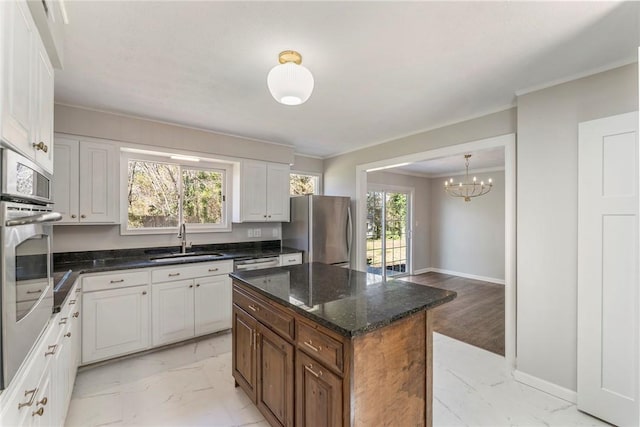 kitchen featuring white cabinetry, sink, dark stone counters, a kitchen island, and appliances with stainless steel finishes