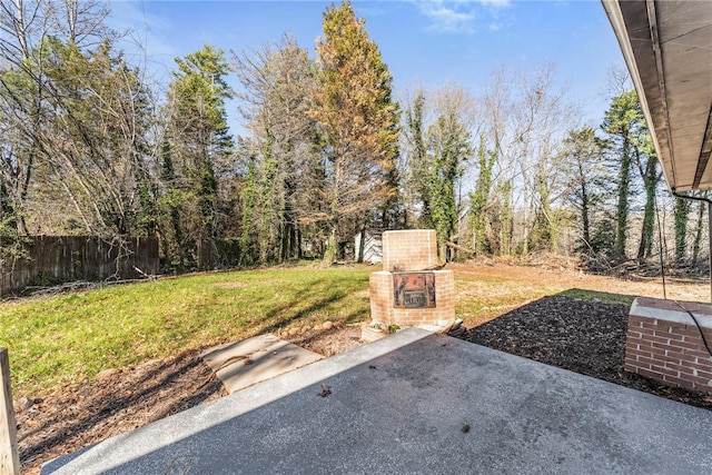 view of yard featuring an outdoor brick fireplace and a patio area