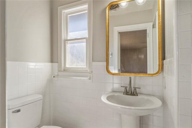 bathroom featuring toilet, tile walls, and sink