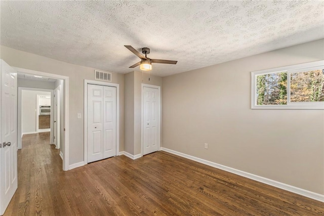 unfurnished bedroom with ceiling fan, dark hardwood / wood-style flooring, and a textured ceiling