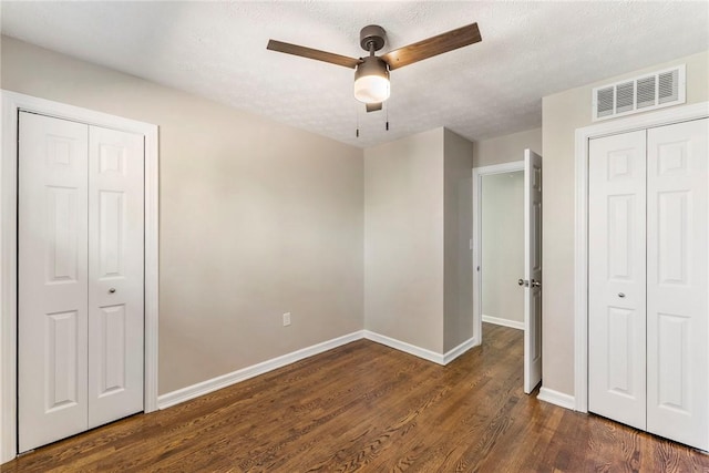 unfurnished bedroom featuring ceiling fan, dark hardwood / wood-style floors, and a textured ceiling