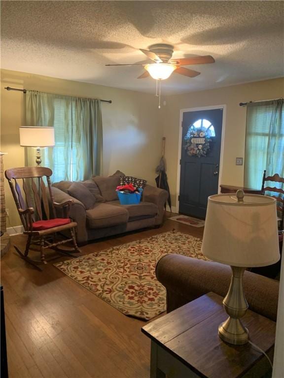 living room with hardwood / wood-style flooring, ceiling fan, and a textured ceiling