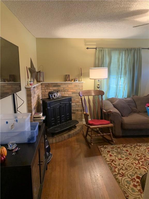 living room featuring a textured ceiling, hardwood / wood-style flooring, and a wood stove