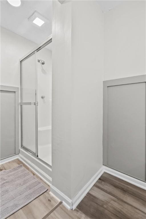 bathroom with wood-type flooring and a shower with door