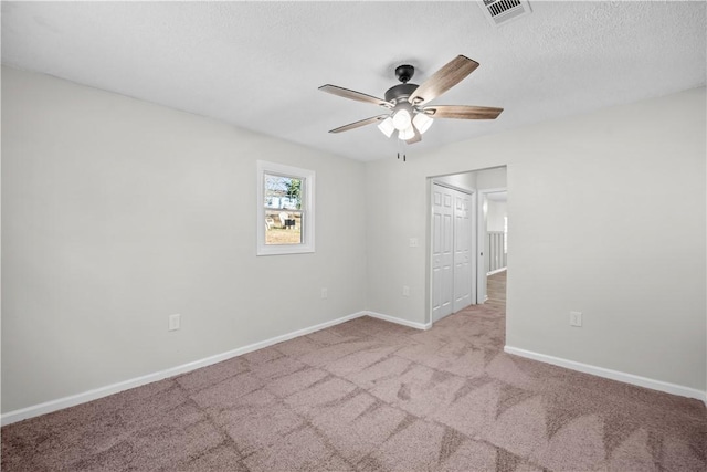 carpeted spare room featuring ceiling fan and a textured ceiling