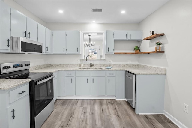 kitchen featuring white cabinets, stainless steel appliances, sink, light hardwood / wood-style flooring, and a chandelier