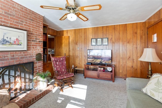 carpeted living room with crown molding, a fireplace, ceiling fan, and wood walls