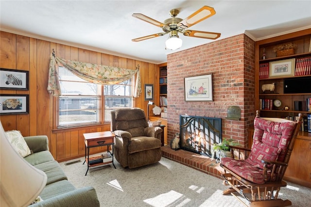 living room with wood walls, light carpet, ceiling fan, ornamental molding, and a fireplace