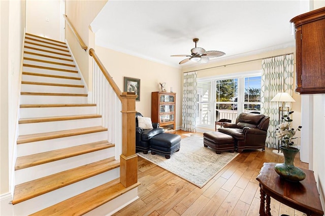 living room with ceiling fan, light wood-type flooring, and ornamental molding