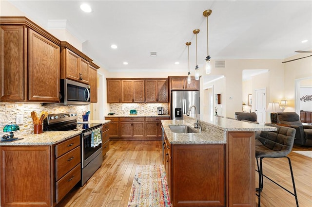 kitchen with decorative backsplash, stainless steel appliances, crown molding, sink, and decorative light fixtures