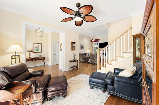 living room with hardwood / wood-style flooring, ceiling fan, and crown molding