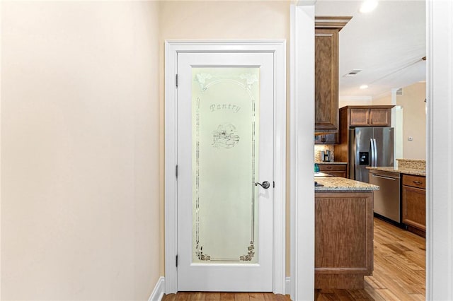 interior space with light stone countertops, light hardwood / wood-style floors, and appliances with stainless steel finishes