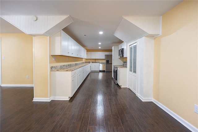 kitchen featuring appliances with stainless steel finishes, dark hardwood / wood-style floors, white cabinetry, and light stone counters