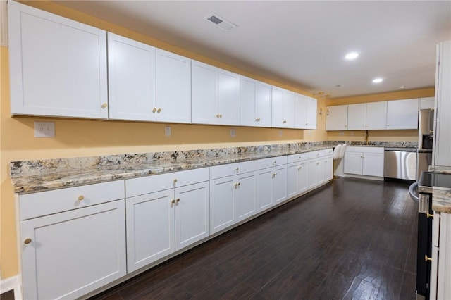 kitchen with white cabinets, light stone counters, dark hardwood / wood-style flooring, and stainless steel appliances