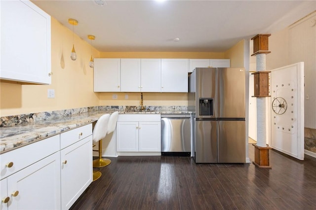 kitchen featuring dark wood-type flooring, hanging light fixtures, stainless steel appliances, light stone counters, and white cabinets