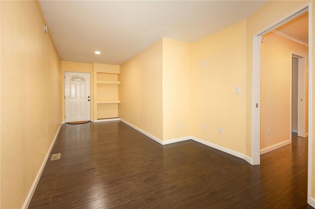 empty room featuring built in shelves and dark hardwood / wood-style floors