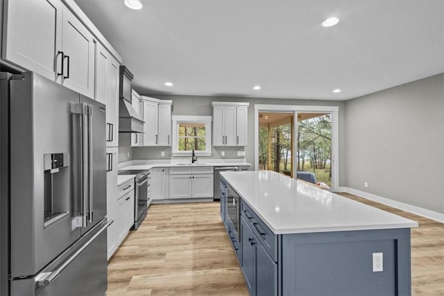 kitchen with white cabinets, a center island, stainless steel appliances, and light hardwood / wood-style flooring