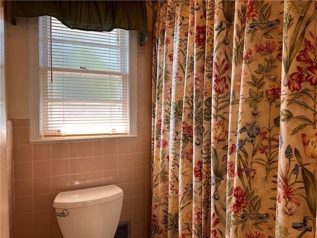 bathroom with toilet and tile walls