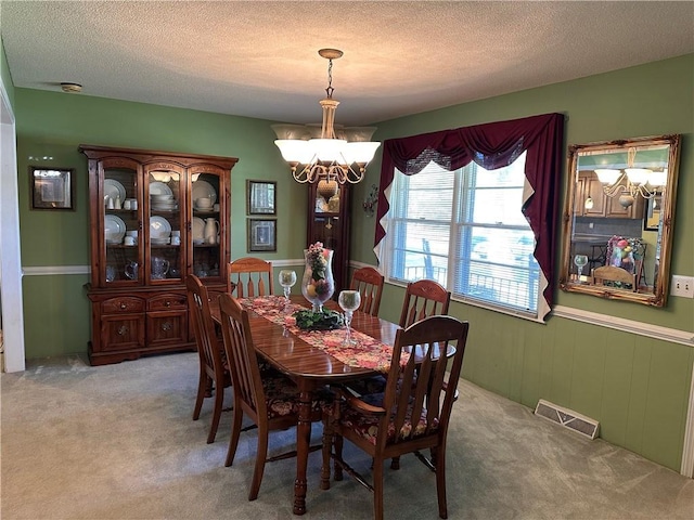 dining area featuring a chandelier, light carpet, and a textured ceiling