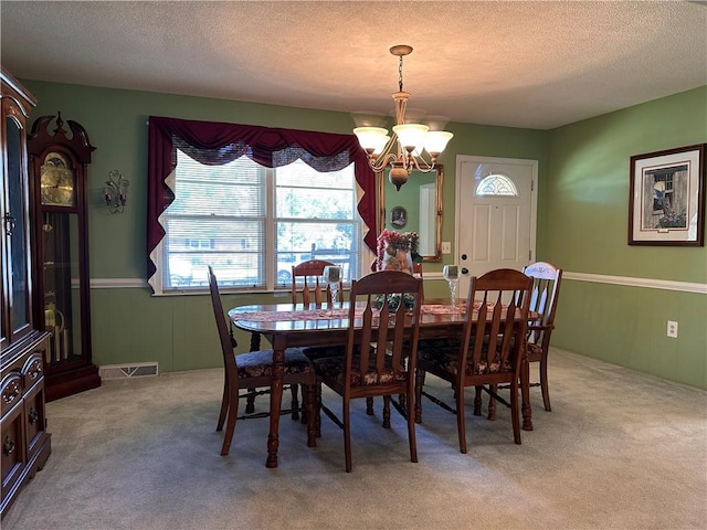 carpeted dining room with a chandelier and a textured ceiling