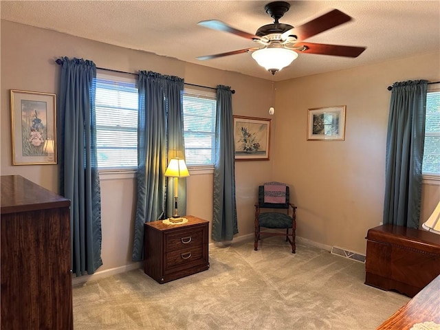 living area featuring a textured ceiling, light colored carpet, and ceiling fan