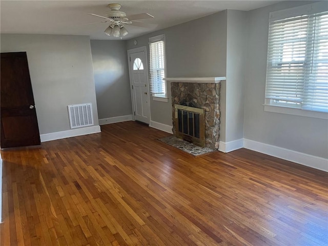 unfurnished living room featuring a fireplace, ceiling fan, and dark wood-type flooring