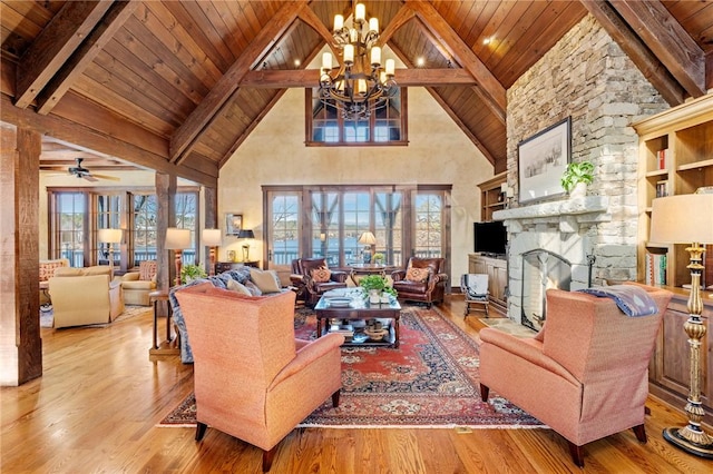 living room with beam ceiling, light hardwood / wood-style floors, high vaulted ceiling, and a stone fireplace