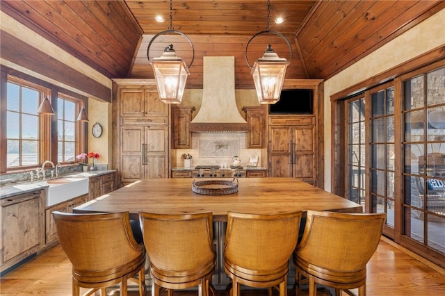 kitchen featuring a center island, sink, vaulted ceiling, range hood, and wood ceiling