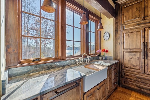 interior space featuring plenty of natural light, wood-type flooring, sink, and stone counters