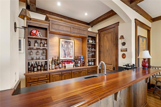 bar with wood counters, hardwood / wood-style floors, beamed ceiling, and sink