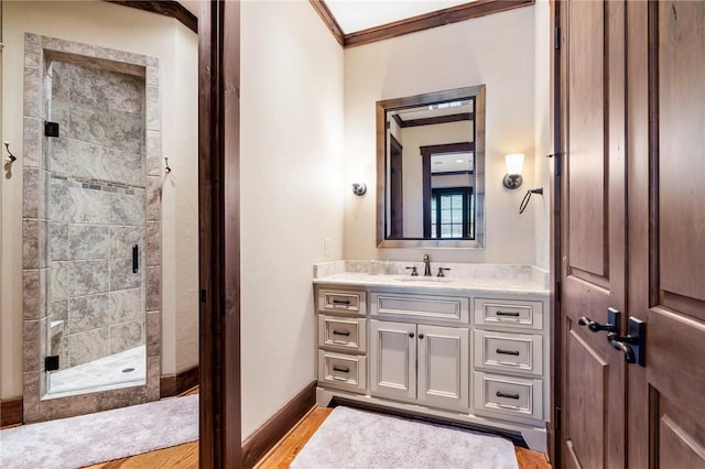 bathroom featuring wood-type flooring, vanity, a shower with door, and crown molding