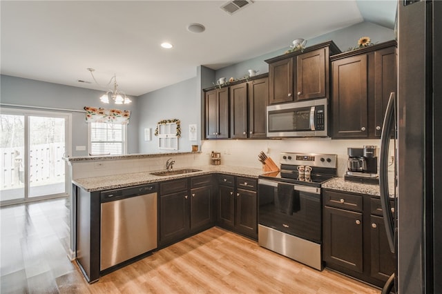 kitchen with kitchen peninsula, tasteful backsplash, stainless steel appliances, sink, and a notable chandelier