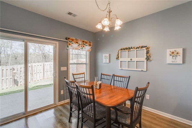 dining space with hardwood / wood-style floors and a notable chandelier