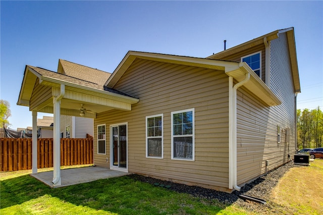 rear view of house with ceiling fan, a yard, and a patio