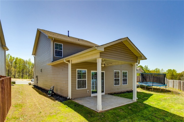 rear view of property featuring ceiling fan, a yard, a patio, and a trampoline