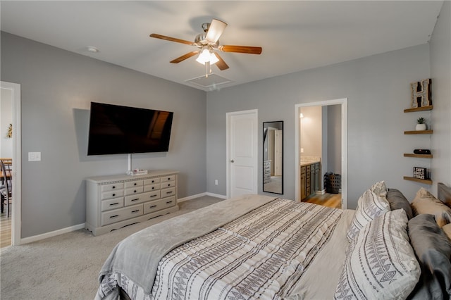 bedroom with ceiling fan, light colored carpet, and connected bathroom