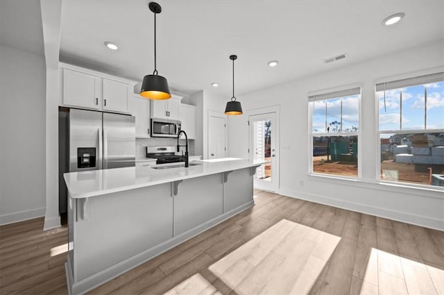 kitchen with white cabinetry, sink, a spacious island, a breakfast bar area, and appliances with stainless steel finishes