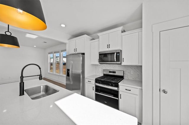 kitchen with backsplash, stainless steel appliances, sink, decorative light fixtures, and white cabinets