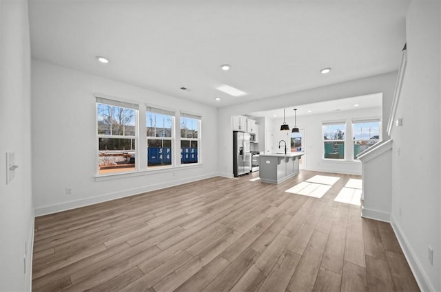 unfurnished living room with light hardwood / wood-style floors and sink