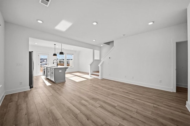 unfurnished living room with light hardwood / wood-style floors and sink