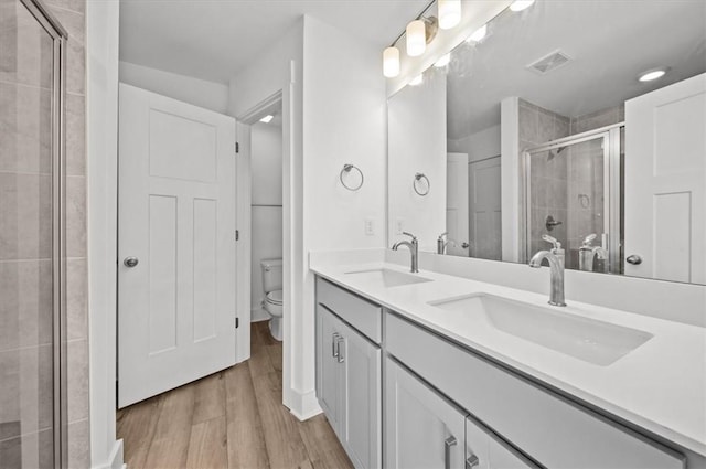 bathroom featuring vanity, toilet, wood-type flooring, and walk in shower