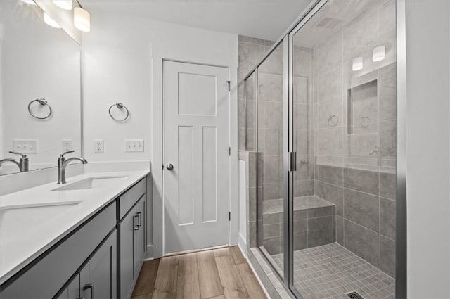 bathroom with hardwood / wood-style flooring, vanity, and a shower with shower door