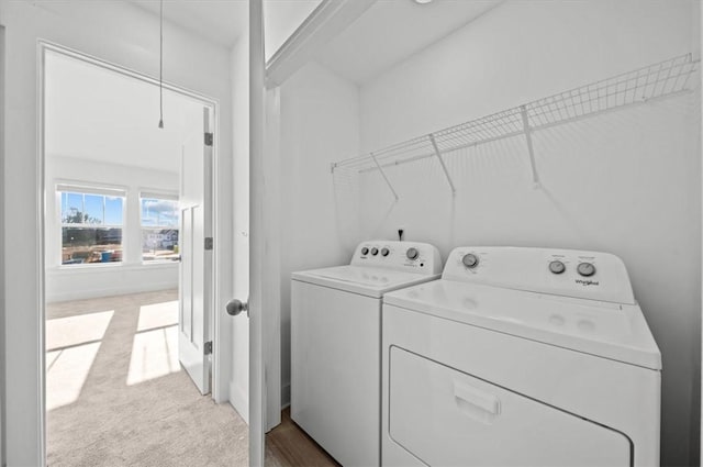 clothes washing area with washing machine and clothes dryer and light colored carpet