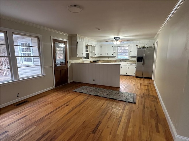 kitchen featuring white cabinets, stainless steel fridge with ice dispenser, crown molding, and a wealth of natural light