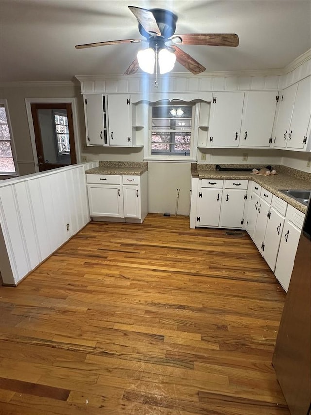 kitchen with sink, crown molding, light hardwood / wood-style flooring, ceiling fan, and white cabinetry