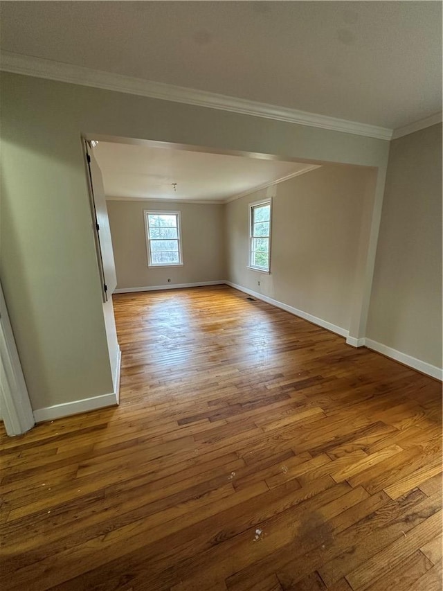 spare room featuring wood-type flooring and crown molding