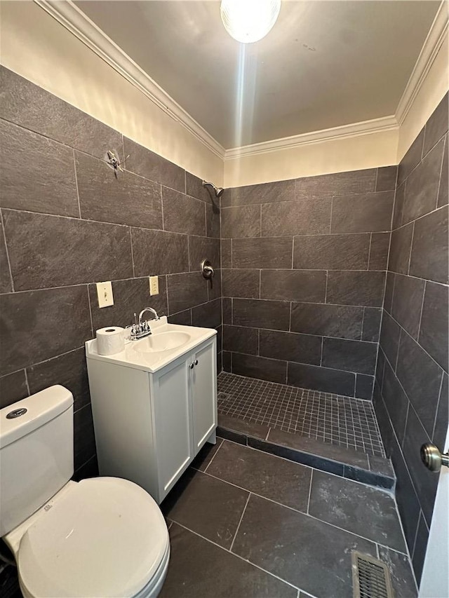 bathroom with tiled shower, toilet, vanity, tile walls, and ornamental molding